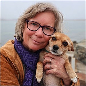 Woman smiling with small dog on beach