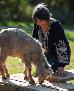woman kneeling with goat