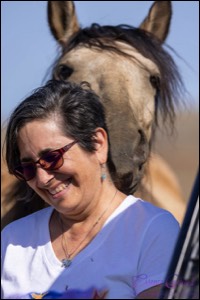 Woman smiling with horse nuzzling her neck