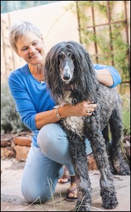 Woman smiling holding Afghan hound